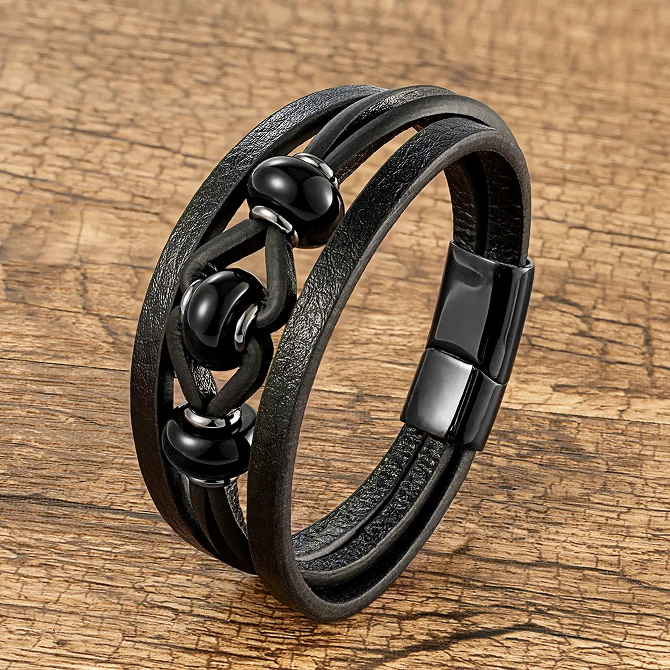 Bracelet en cuir noir à cordon, avec trois brins, comportant des perles en pierre naturelle noires et une fermeture magnétique.
