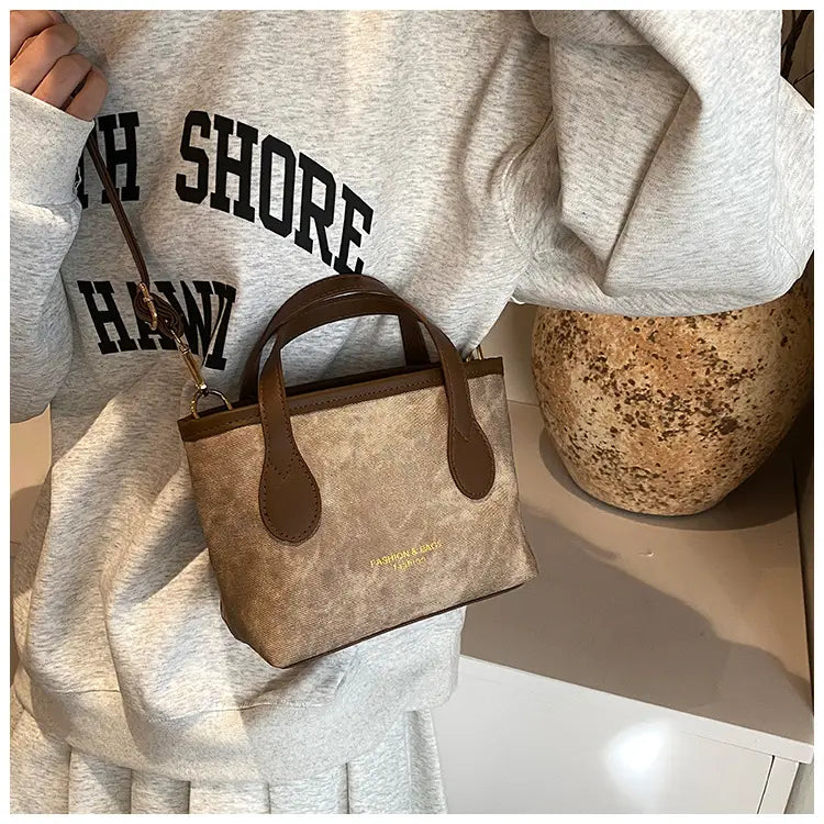Beige and brown retro bucket bag textured canvas mini tote handbag with leather handles designed as a shoulder bag.