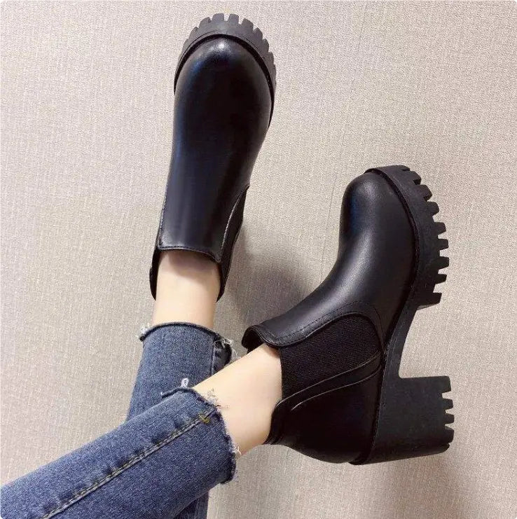 Women’s black leather chunky heel ankle boots featuring chelsea style with chunky textured soles and a mid-height heel.