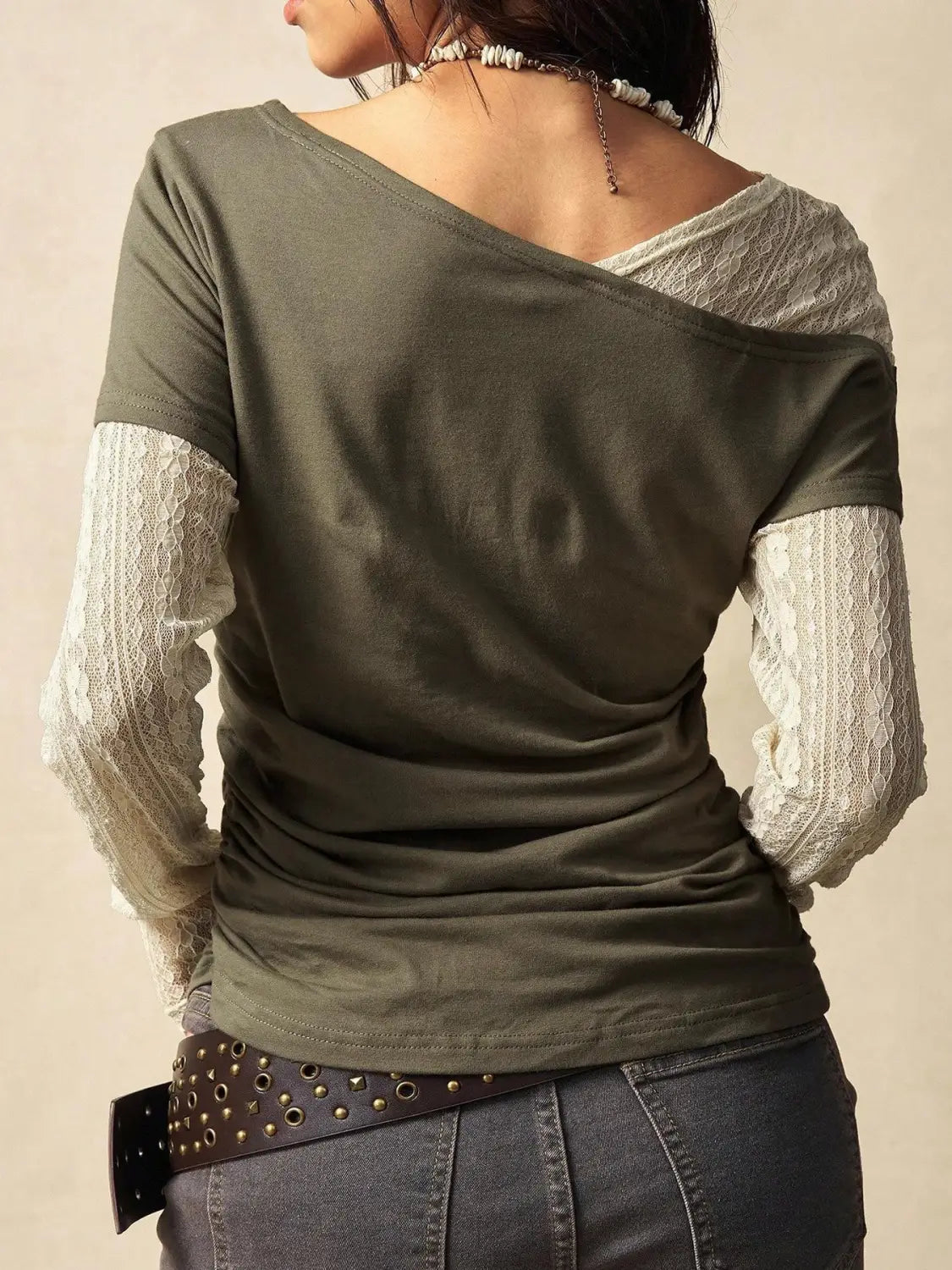 Olive green knitted short-sleeved top featuring sheer lace sleeves and a draped asymmetrical neckline for an elegant off shoulder look.