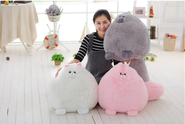 A plush Persian cat soft fluffy round pillow toy in soft pink with a fluffy texture and embroidered facial features.