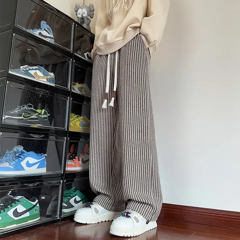 Men wide leg herringbone drawstring trousers featuring beige and dark gray vertical striped pattern with an elastic waist and drawstrings.