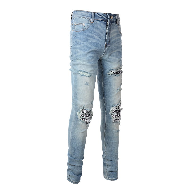 Men’s slim fit light wash denim jeans with distressed ripped knees and intricate black and silver embroidery.
