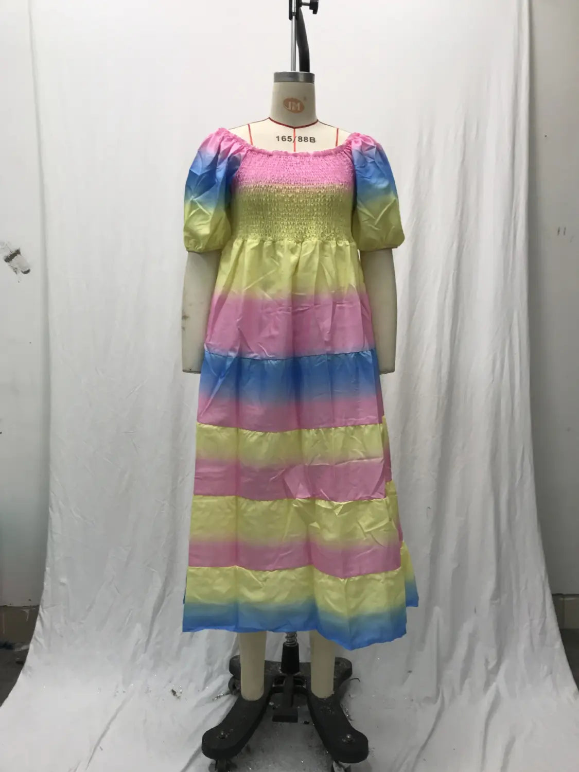 A vibrant rainbow-striped floral print smocked tiered midi dress with a square neckline and puffy sleeves displayed on a mannequin.