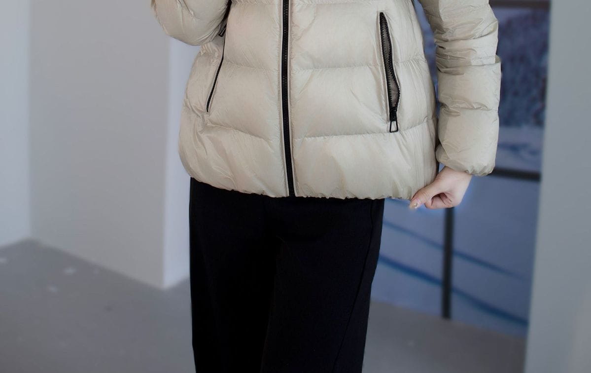 Beige kurze Steppjacke aus Daunen für Damen mit schwarzen Reißverschlussakzenten, als Winter-Puffer konzipiert.