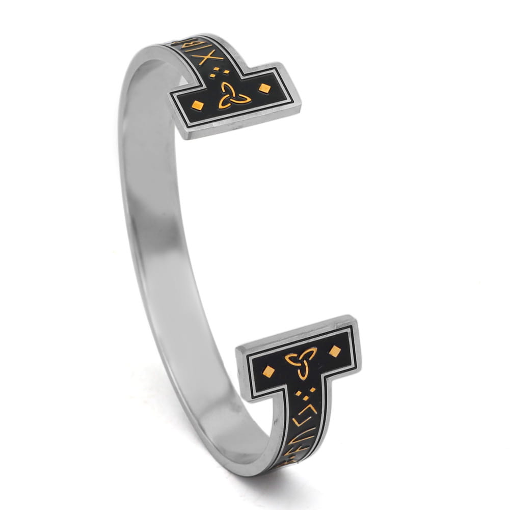 Adjustable Viking rune titanium steel open cuff bracelet in silver tone with black inlaid panels featuring gold-colored runic inscriptions and a central triquetra symbol.