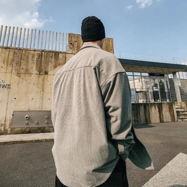 Eine Person, die eine Herren-Retro-Utility-Hemdjacke aus Cord mit lockerer Passform in Beige trägt, mit langen Ärmeln und einer entspannten Passform.
