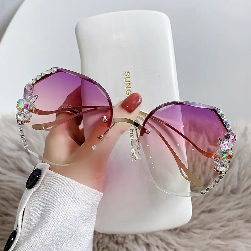Gafas de sol de lujo con pedrería de mariposa tipo cristal y protección UV400, con lentes degradadas en color rosa, adornos con pedrería y monturas metálicas de tono dorado.