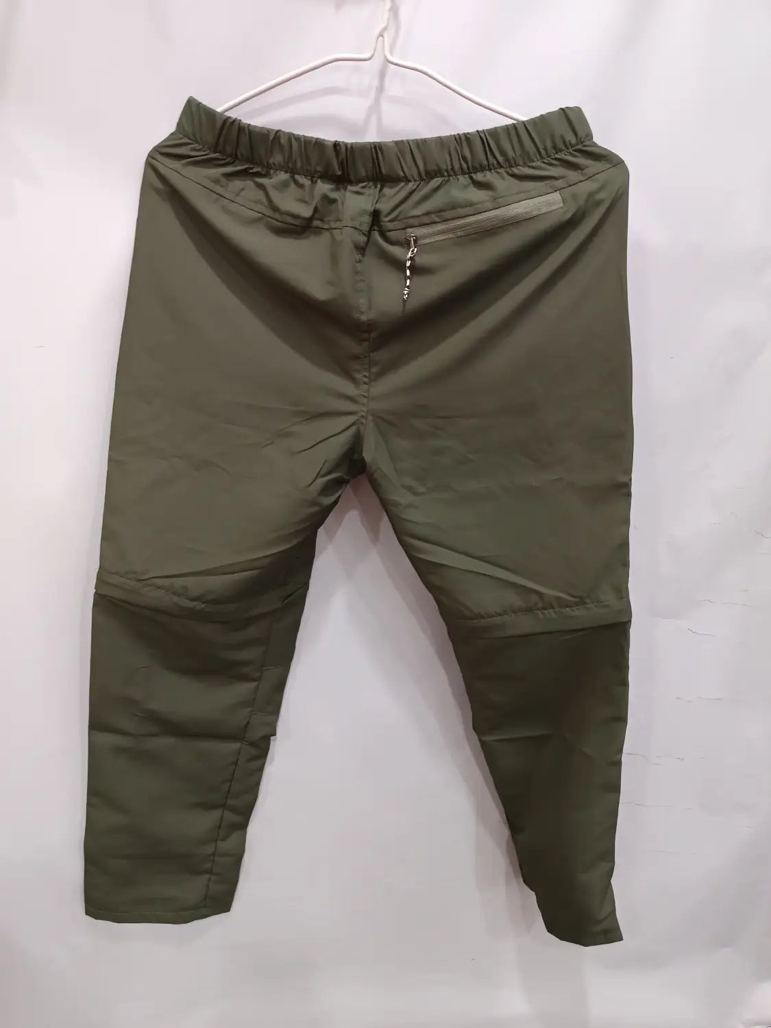 Convertible tactical hiking pants in olive green featuring elastic waist, zippered side pocket, and subtle stitching details.