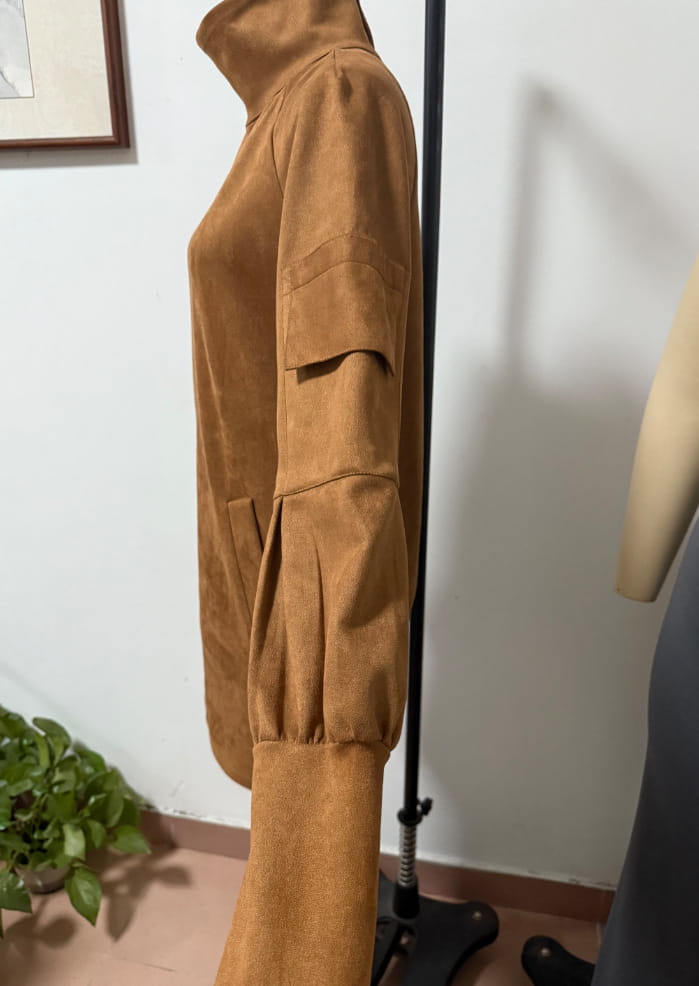 A tan suede turtleneck cargo mini dress with long sleeves featuring a high collar and patch pockets.