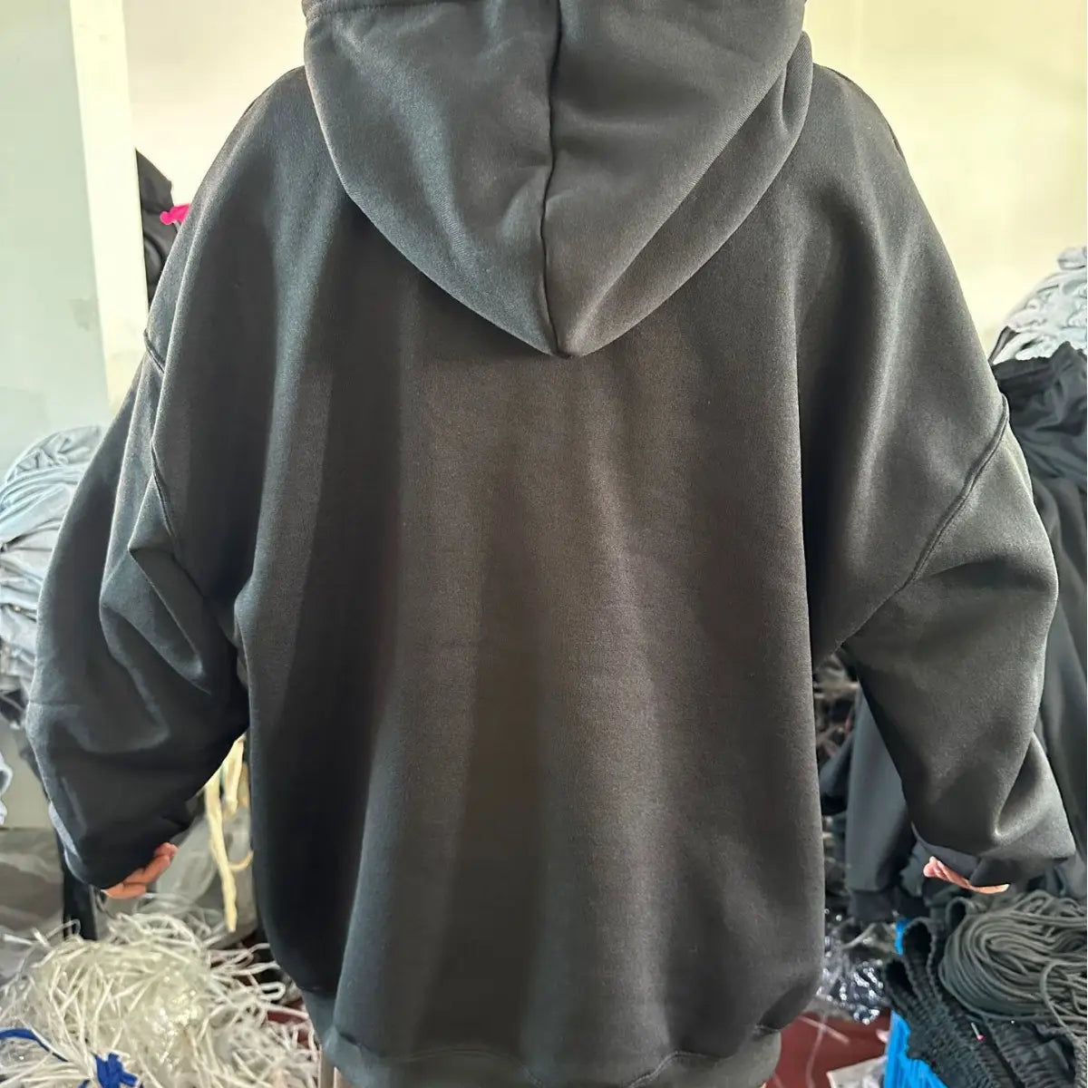 Herren-Pulloverhoodie mit Dropshoulder-Schnitt, einfarbig, in Schwarz, mit weich strukturierter Stoffqualität und entspannter Passform.