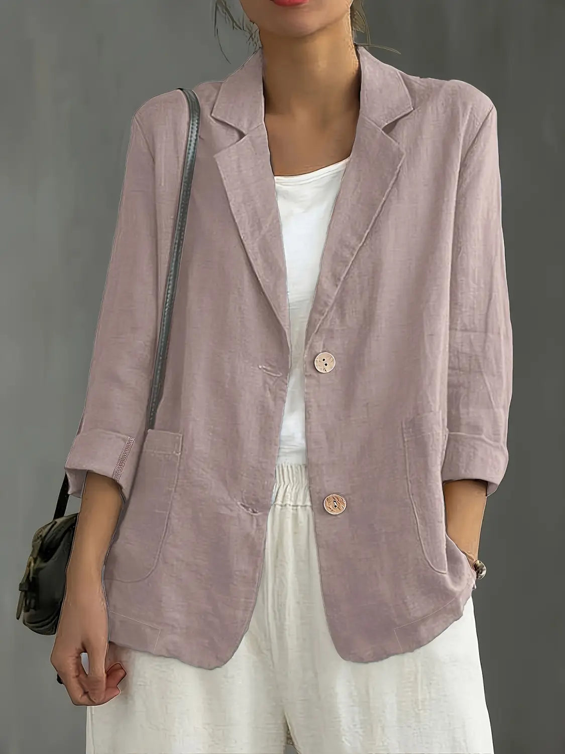 Un blazer de lino lila suave para mujer con mangas remangadas y botones rosa a juego, diseñado para ropa de trabajo casual.