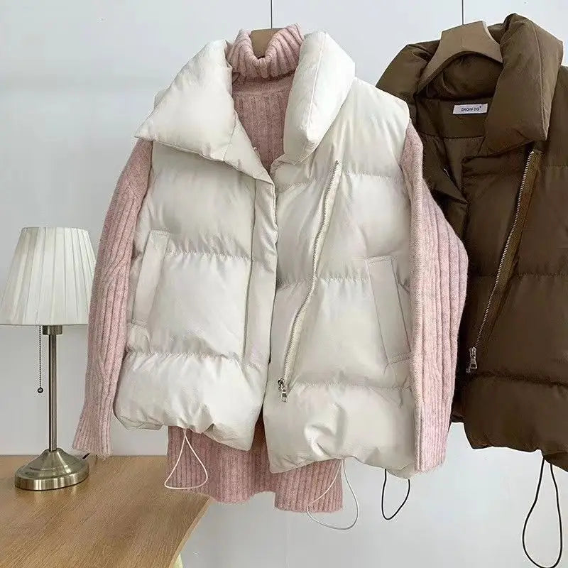 Cream-colored quilted puffer vest with a plush white collar and pink ribbed knit sleeves designed as loose sleeveless outerwear for women.
