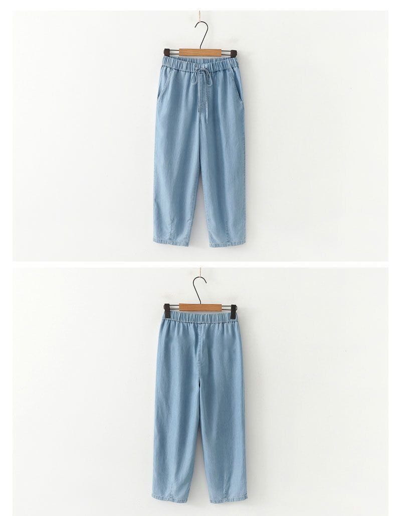 Light blue denim harem jeans high waisted drawstring pants with elastic waistband shown from the front.