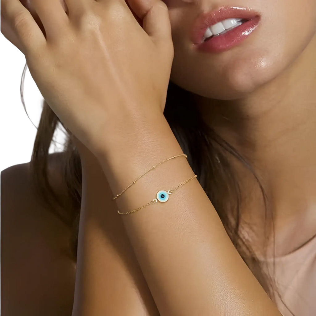 Delicate 14k gold filled layered bracelet featuring a small round blue evil eye charm with adjustable design