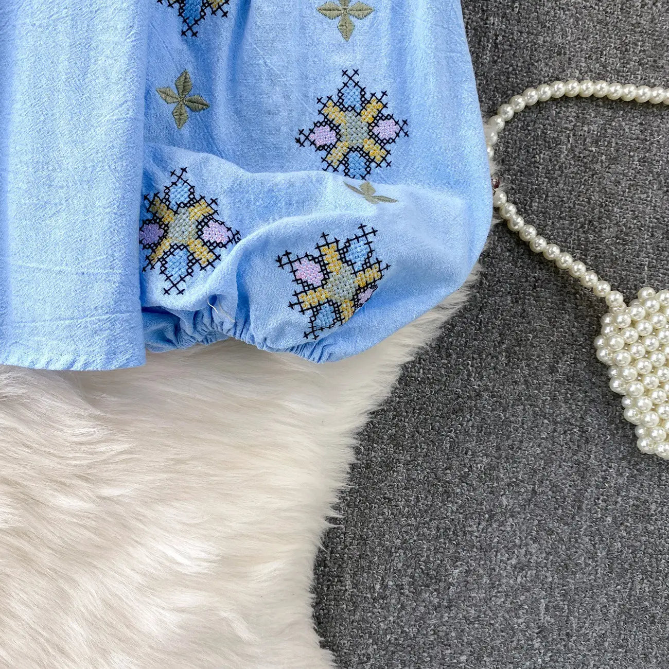 Light blue cotton skirt with colorful cross-stitch floral patterns paired with an embroidered lantern sleeve tie neck blouse.