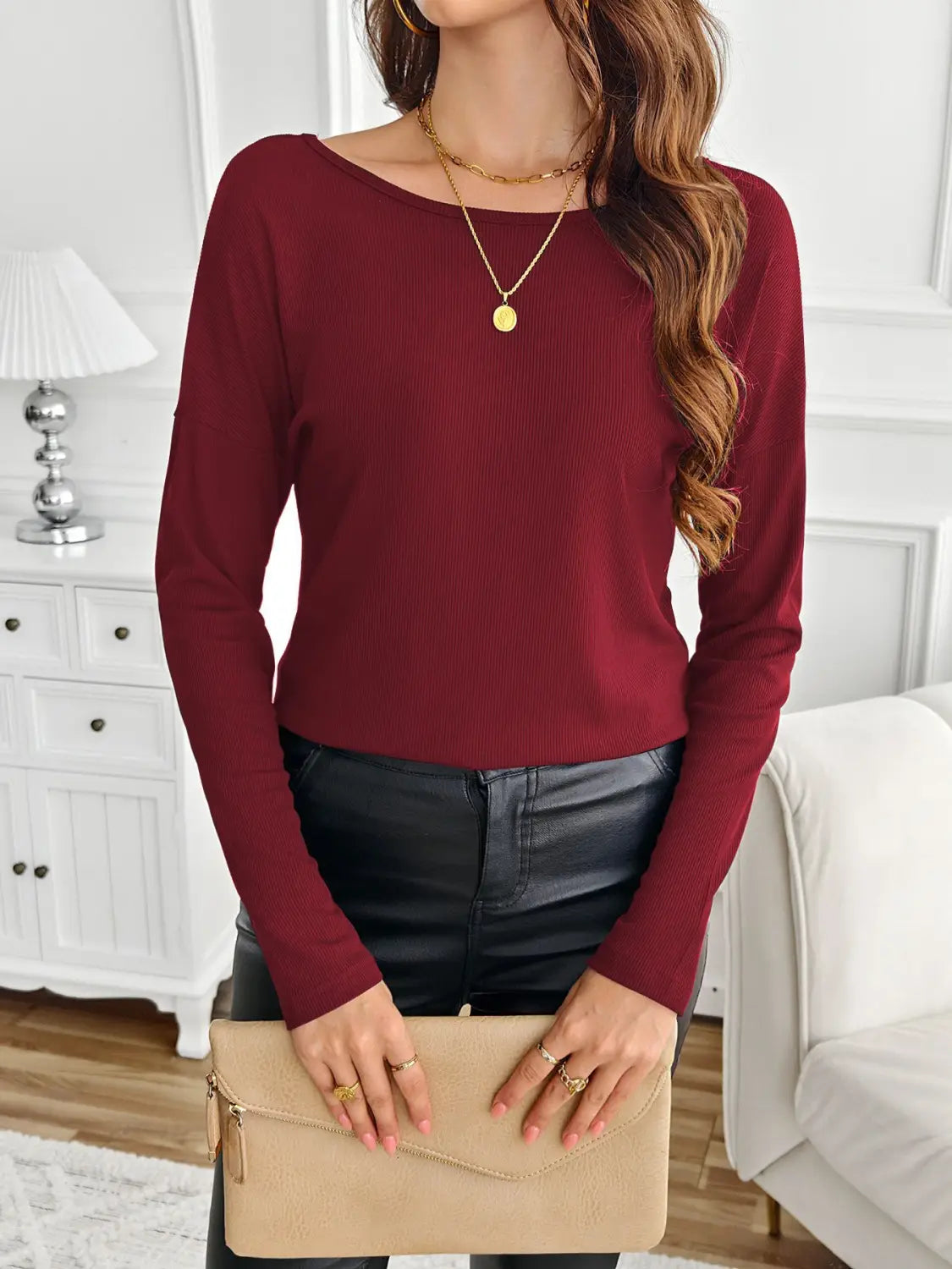 A maroon ribbed long sleeve top with a boat neckline featuring a butterfly lace back detail.