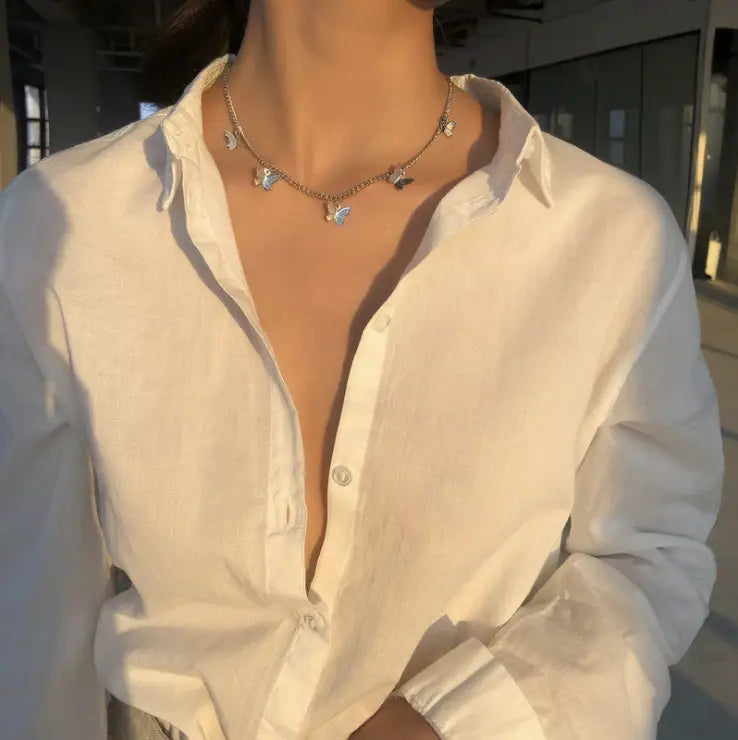 A delicate silver chain necklace adorned with small intricately designed butterfly charms from the elegant butterfly charm choker necklace collection in gold and silver.