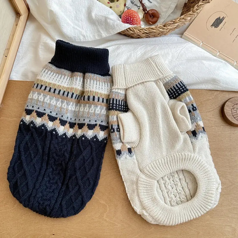 Zwei Hundepullover aus weichem Strick in Fair-Isle-Blau für Heimtierbedarf mit einem marineblauen Zopfmuster und einem cremefarbenen geometrischen Streifenmuster.