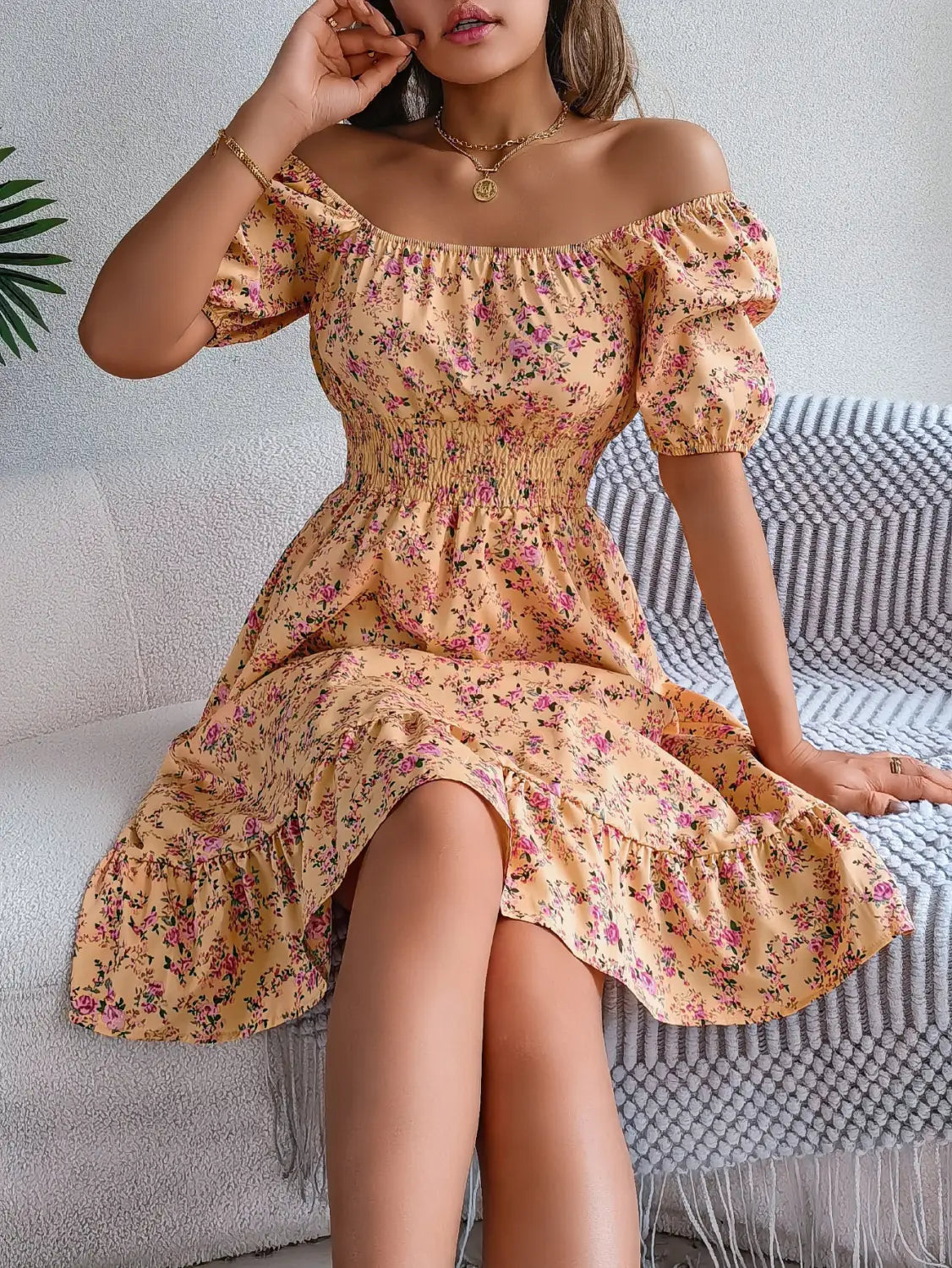 Robe d’été décolletée florale pêche clair, avec manches bouffantes et ourlet à volants.
