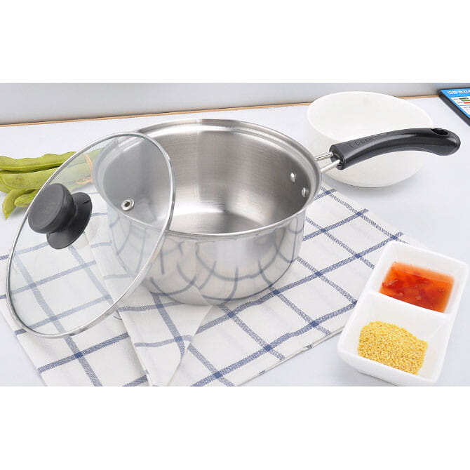 Cazo de acero inoxidable con asa negra y tapa de vidrio transparente con pomo negro de un juego de utensilios de cocina de acero inoxidable para inducción con tapas de vidrio.