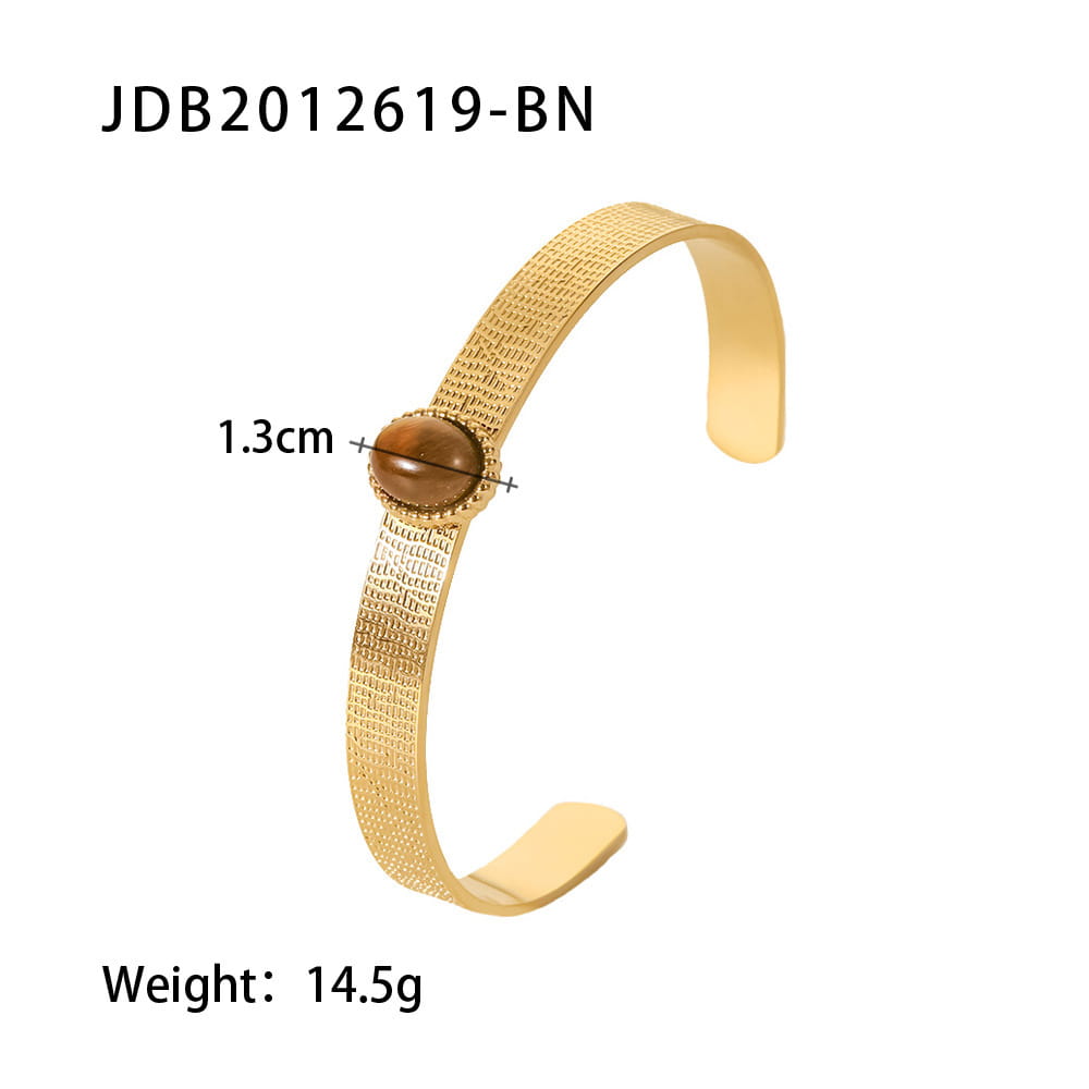 Gold plated stainless steel bangle bracelet with a gold-toned textured cuff and a central amber-colored zirconia gemstone set in an ornate bezel.