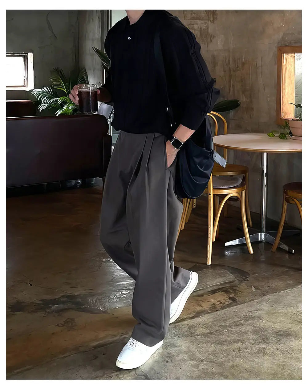 Camisa negra abotonada de manga larga, de ajuste relajado y textura sutil, combinada con pantalones de vestir anchos plisados color gris oscuro para hombre.