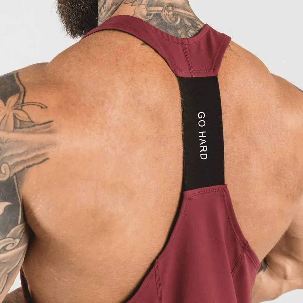 Men’s go hard racerback athletic tank top in maroon with black shoulder strap featuring white go hard text ideal for workouts.