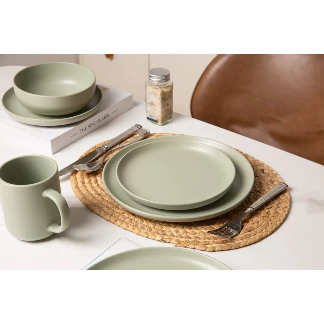 ensemble de vaisselle en grès cérame vert sauge, finition mate, comprenant des assiettes, des bols et une tasse, dans un lot de 12 pièces pour trois personnes.