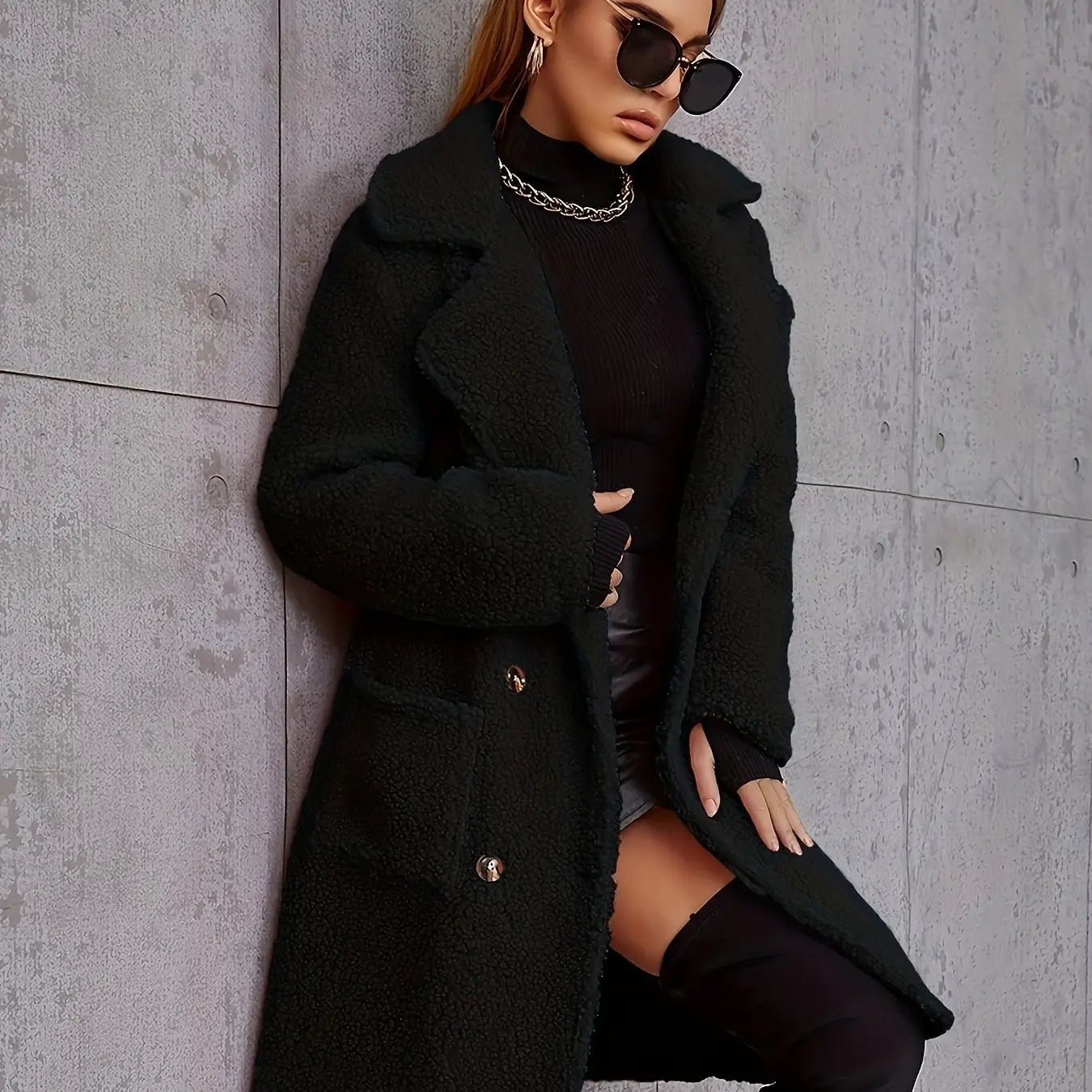 Manteau teddy mi-long doublé en polaire noire, muni de boutons à ton or et d’un extérieur texturé en peau lainée moelleuse.