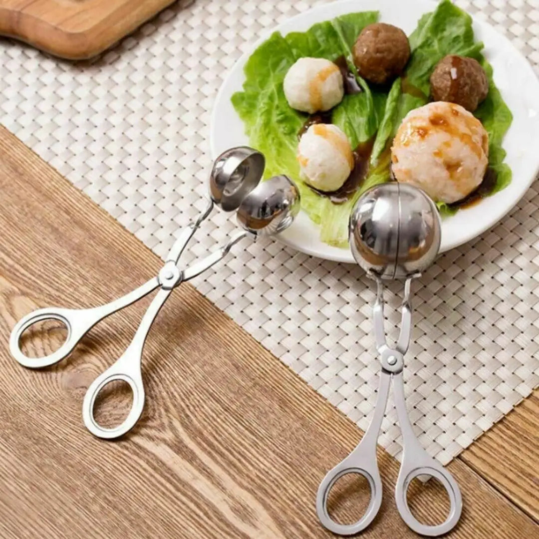 Two stainless steel meatball maker tongs with ball-shaped ergonomic handles designed for portioning and serving spherical foods.
