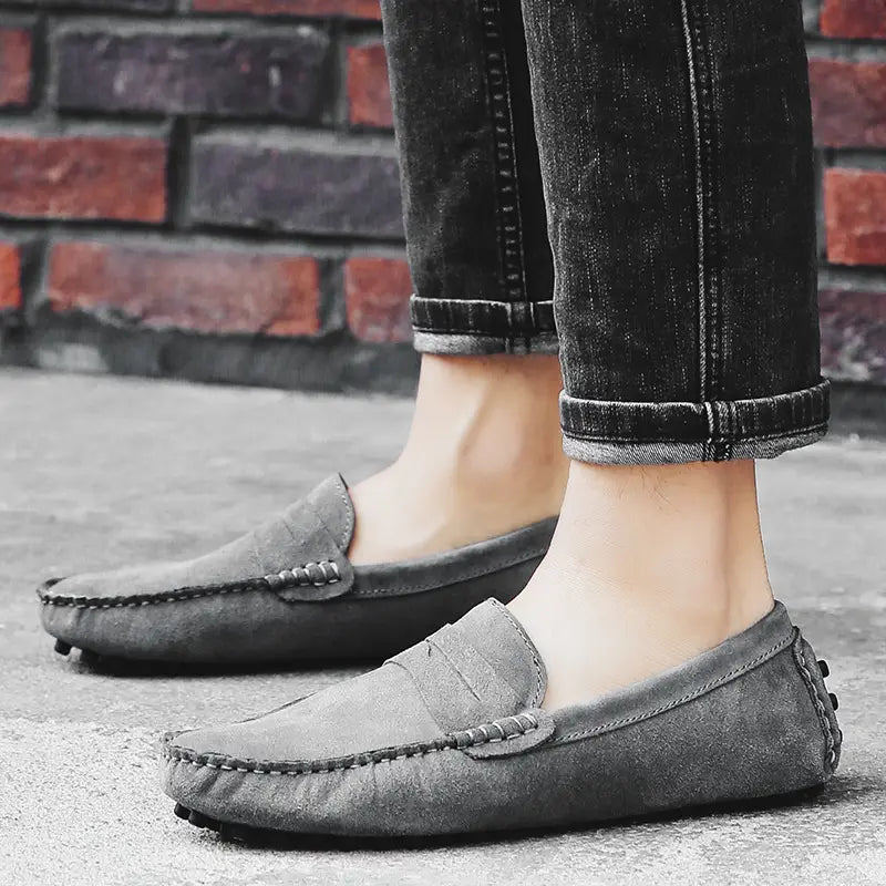 Mocassins en daim gris pour homme, avec des détails cousus classiques et une semelle en caoutchouc durable.