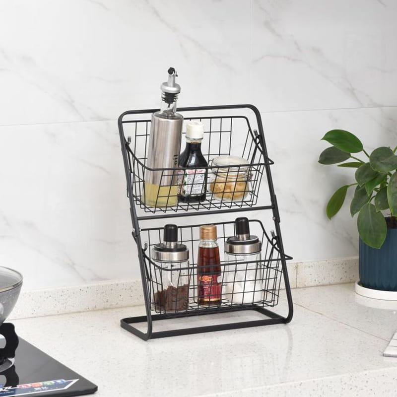 panier à fruits à deux niveaux en fil métallique noir, conçu comme un support de rangement pour la cuisine, pour contenir divers condiments et bouteilles, afin d’assurer un usage ordonné sur le plan de travail