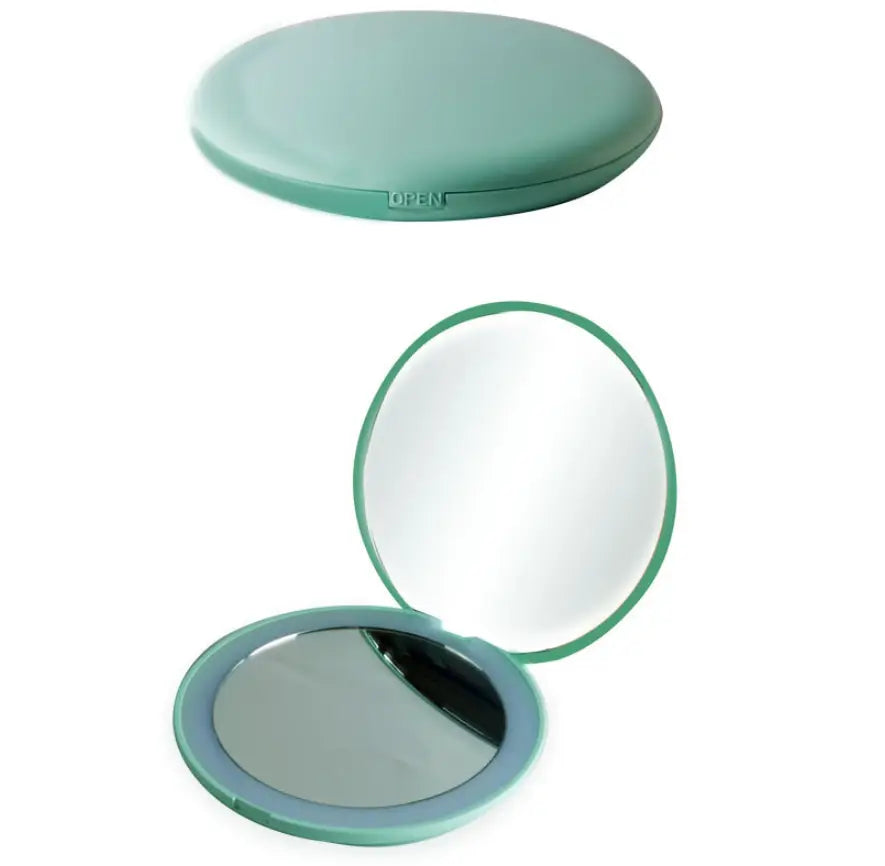 A sleek mint green portable led makeup mirror with 10x magnification featuring a smooth rounded compact case and two mirrored surfaces.
