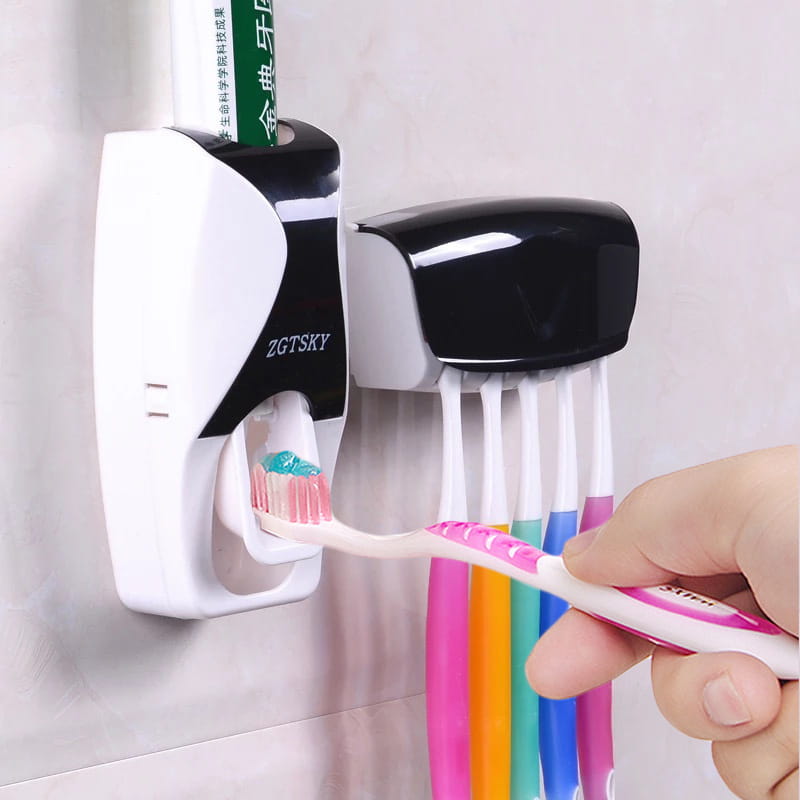 white and black zgtsky automatic toothpaste dispenser and toothbrush holder set holding a green toothpaste tube dispensing teal paste onto a pink-handled toothbrush