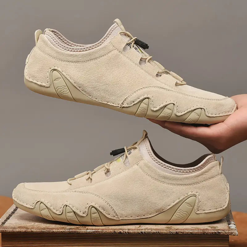 Beige Wildleder-Freizeitschuhe für Herren mit niedrigem Schaft mit gewelltem Gummisohlendesign und schwarzen Ösen für Schnürsenkel.