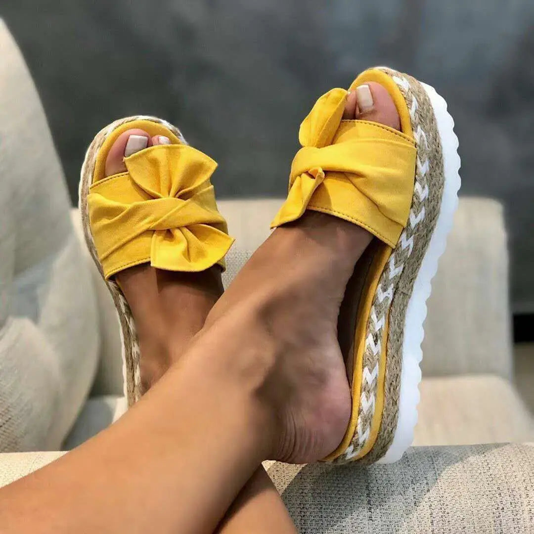 Women platform bow espadrille slide sandals in bright yellow with a wide fabric bow strap and a woven jute sole with a white rubber heel.