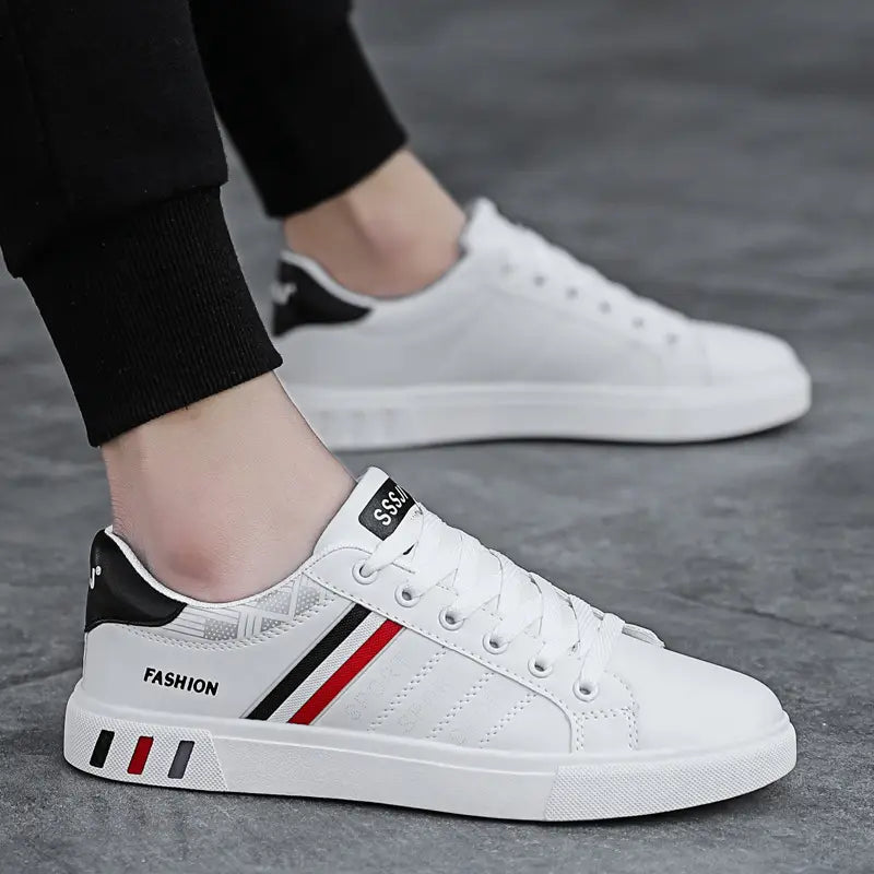 Men’s leather low top sport fashion sneakers in white with black and red stripes featuring a fashion label on the side and a branded tag at the heel.