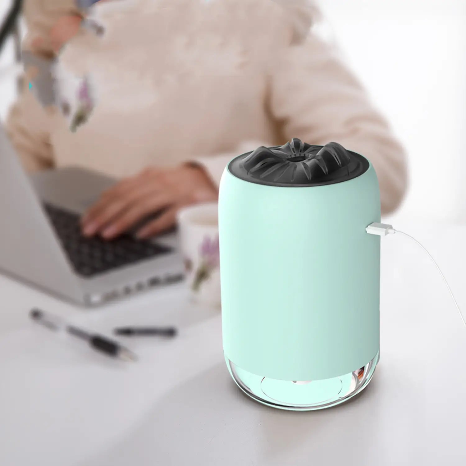 Magic Flame humidifier mini usb ultrasonic aroma diffuser featuring a mint green cylindrical body with a black textured top and clear glass base plugged in via usb cable.