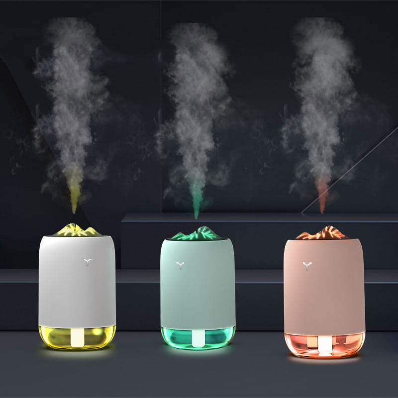 three sleek cylindrical ultrasonic magic flame humidifier mini usb aroma diffusers with mountain-shaped tops and glowing bases in white mint green and blush pink.