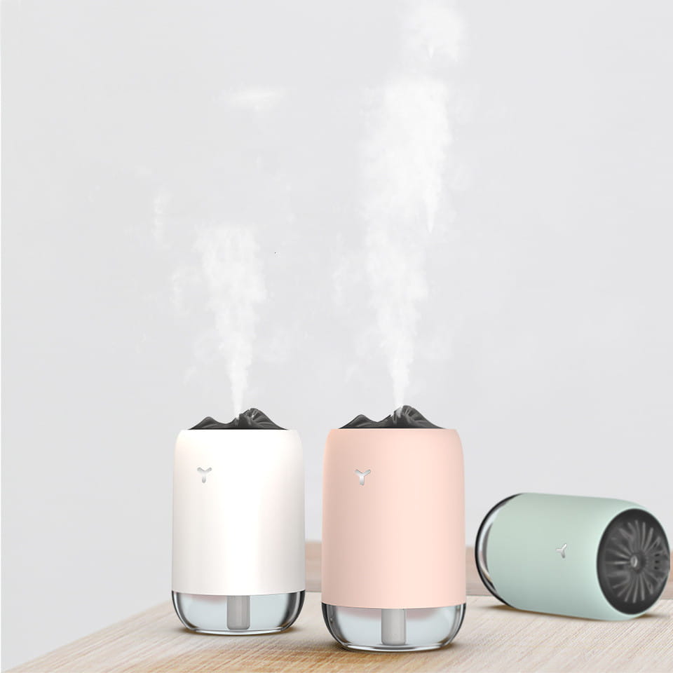 Two sleek cylindrical magic flame humidifier mini usb ultrasonic aroma diffusers in white and blush pink with glass bases emitting gentle mist