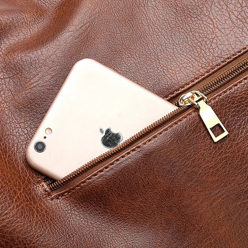 A rose gold iPhone rests partially inside a large capacity brown faux leather zippered hobo shoulder bag with visible stitching and a brass zipper pull.