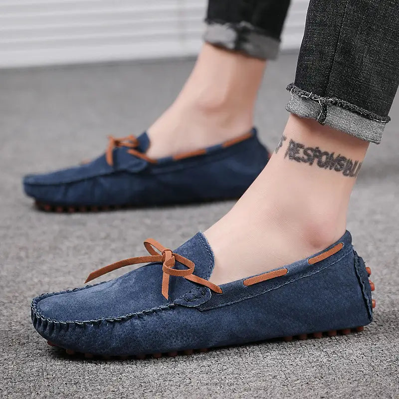 Des mocassins décontractés en suède bleu marine pour la conduite, avec des lacets en cuir camel et des détails de couture conçus comme des mocassins décontractés.