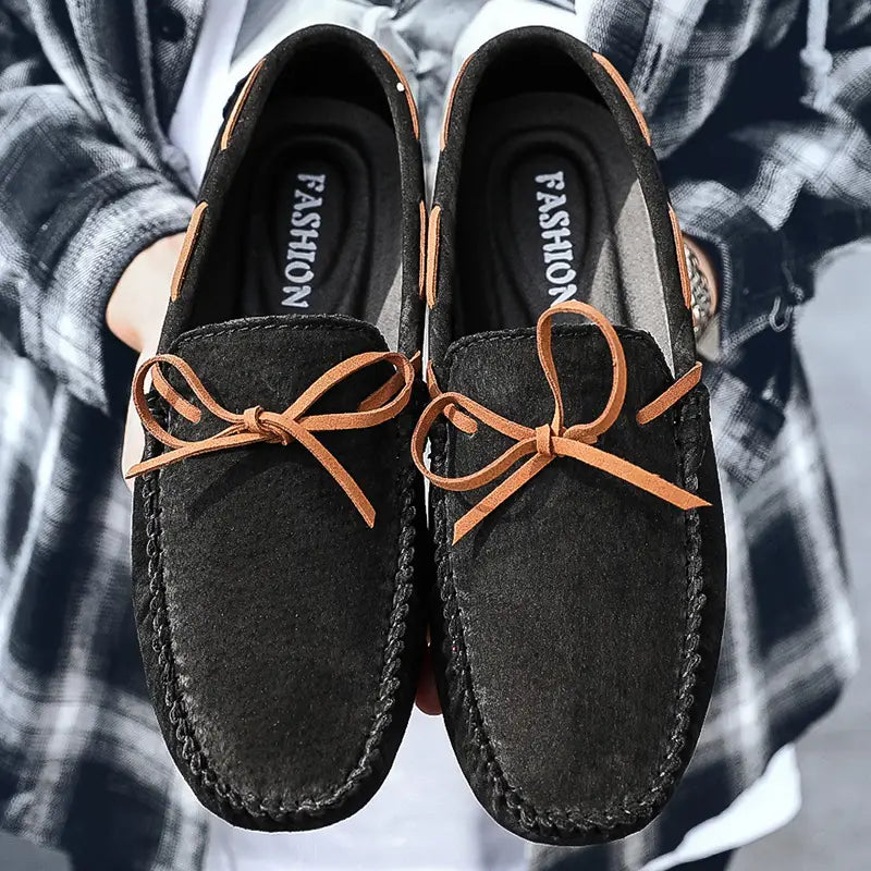 Des mocassins décontractés en suède noir pour la conduite, avec des nœuds en cuir camel et des détails de couture, conçus comme des mocassins décontractés.