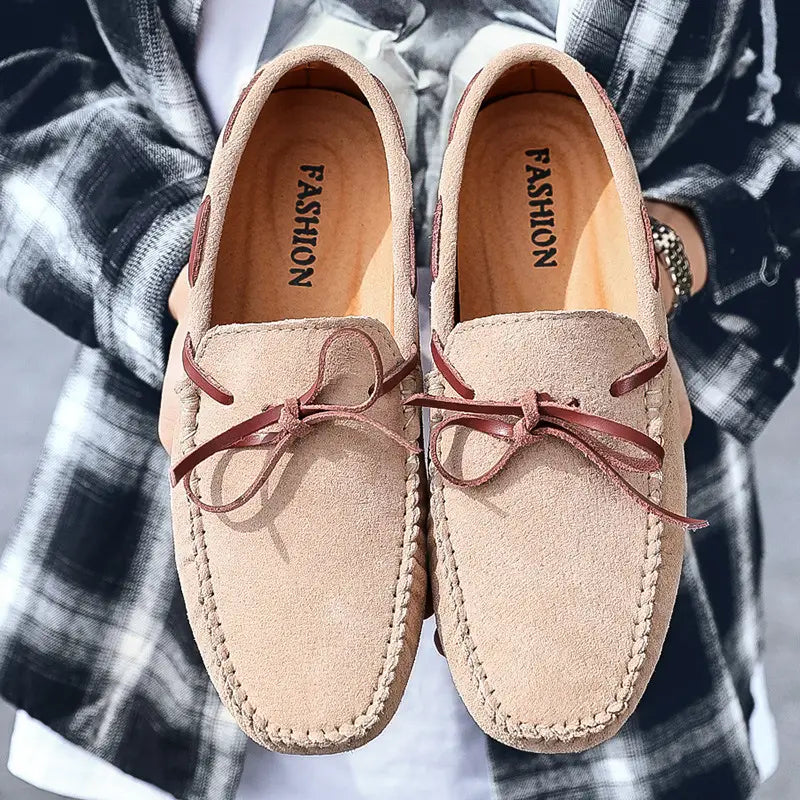 Des mocassins décontractés en suède beige pour la conduite, avec des lacets en cuir marron et une couture.