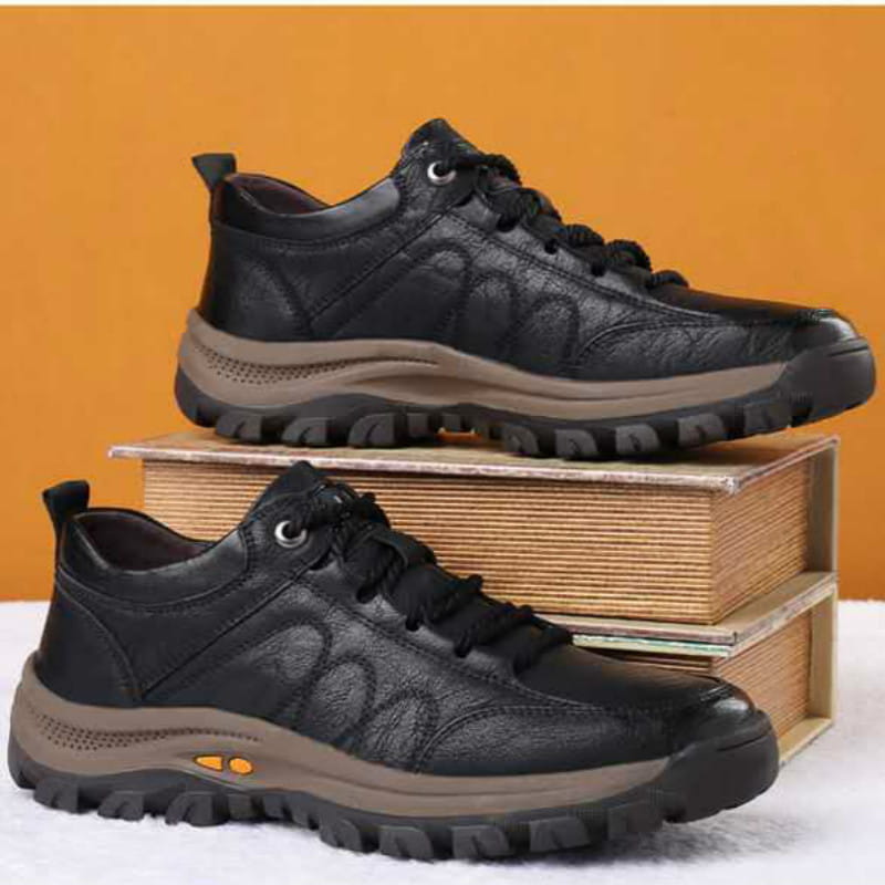 Men’s leather hiking shoes featuring black textured leather uppers, tan midsoles, and rugged black outsoles with orange accents designed for vintage casual outdoor use.