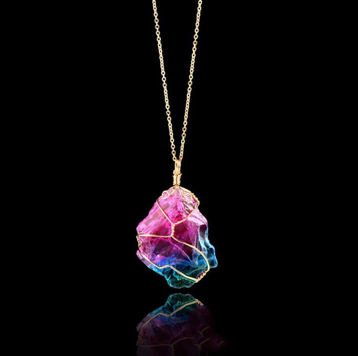 A wire wrapped rainbow quartz crystal pendant necklace featuring a vibrant iridescent crystal with a pink to blue gradient wrapped in delicate gold wire and suspended from a fine gold chain.