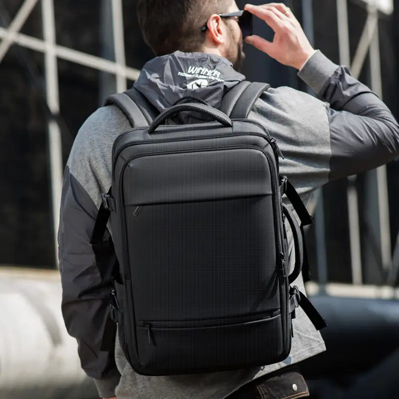 black textured business laptop backpack 20-35l waterproof travel bag with multiple zippered compartments and adjustable shoulder straps shown from the back side