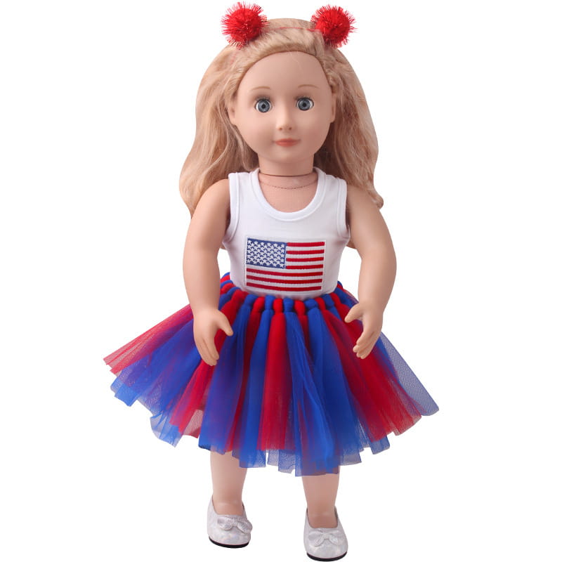 Eine 18-Zoll-Puppe in einer USA- und Malaysia-Flaggen-Tutu-Kleidung mit einem weißen Tanktop mit einem amerikanischen Flaggenmotiv und einem roten sowie blauen Tutu-Rock mit roten Pom-Pom-Haarclips.