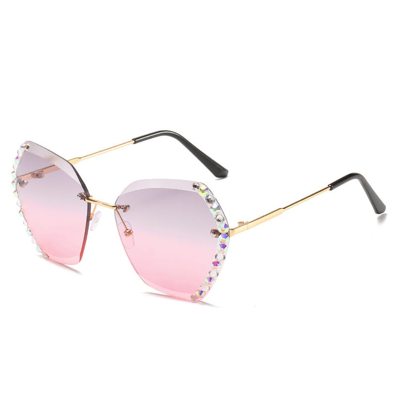 Diamond studded rimless polygonal sunglasses featuring pink gradient lenses with gold metal frames and rhinestone embellishments along the edges.